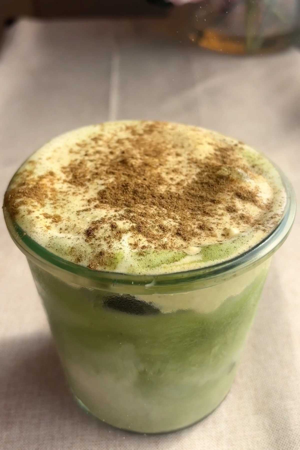 Close-up of pumpkin spice matcha latte topped with thick foam and spice.