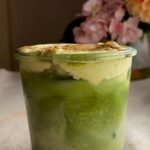 Iced matcha latte with pumpkin cold foam in a glass jar, dusted with pumpkin spice.