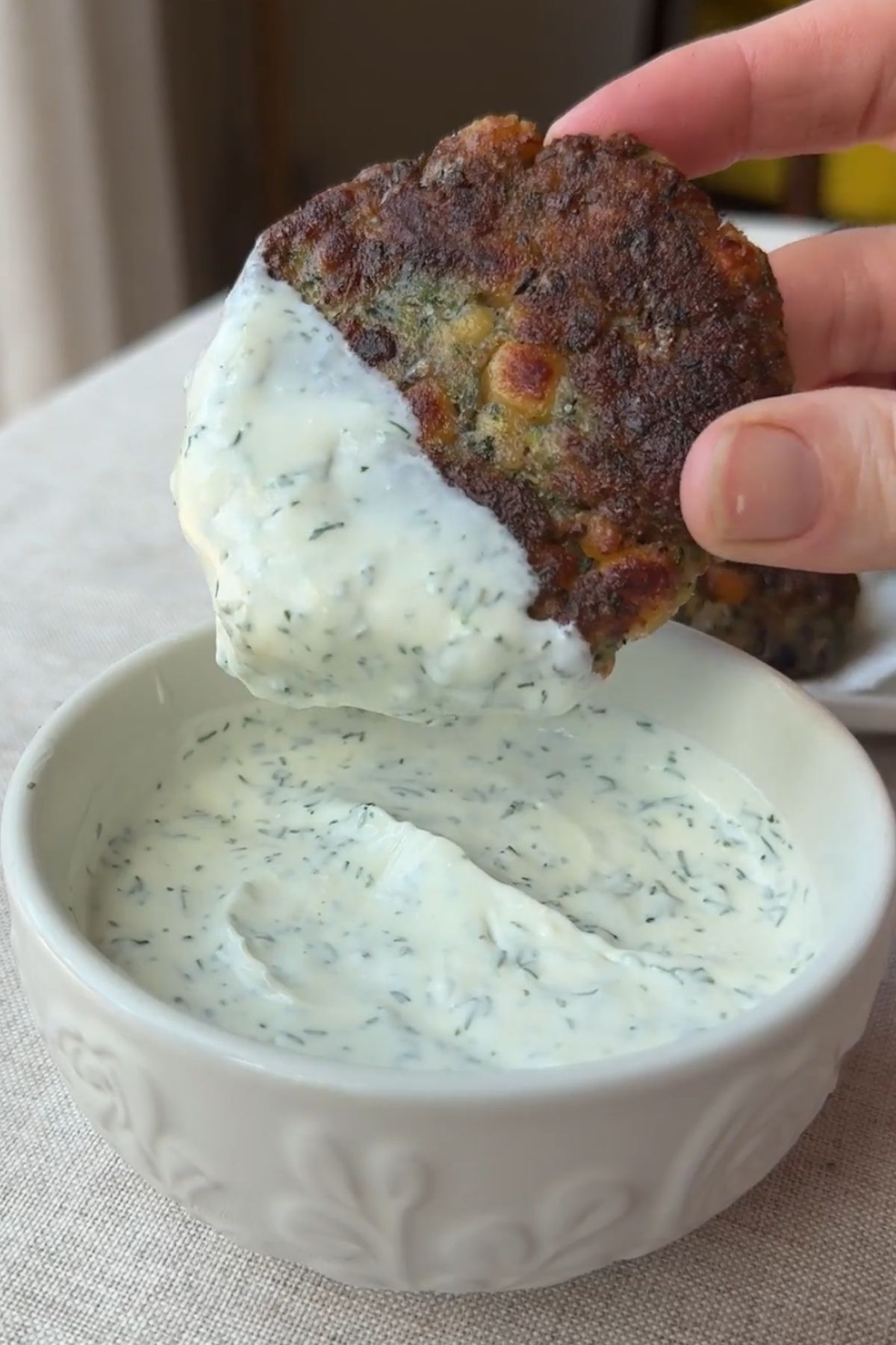 Zucchini chickpea fritters served with a bowl of creamy herb yogurt sauce.