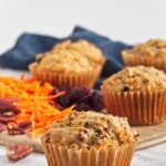 Close-up of vegan carrot cake muffins showing textured tops and paper liners