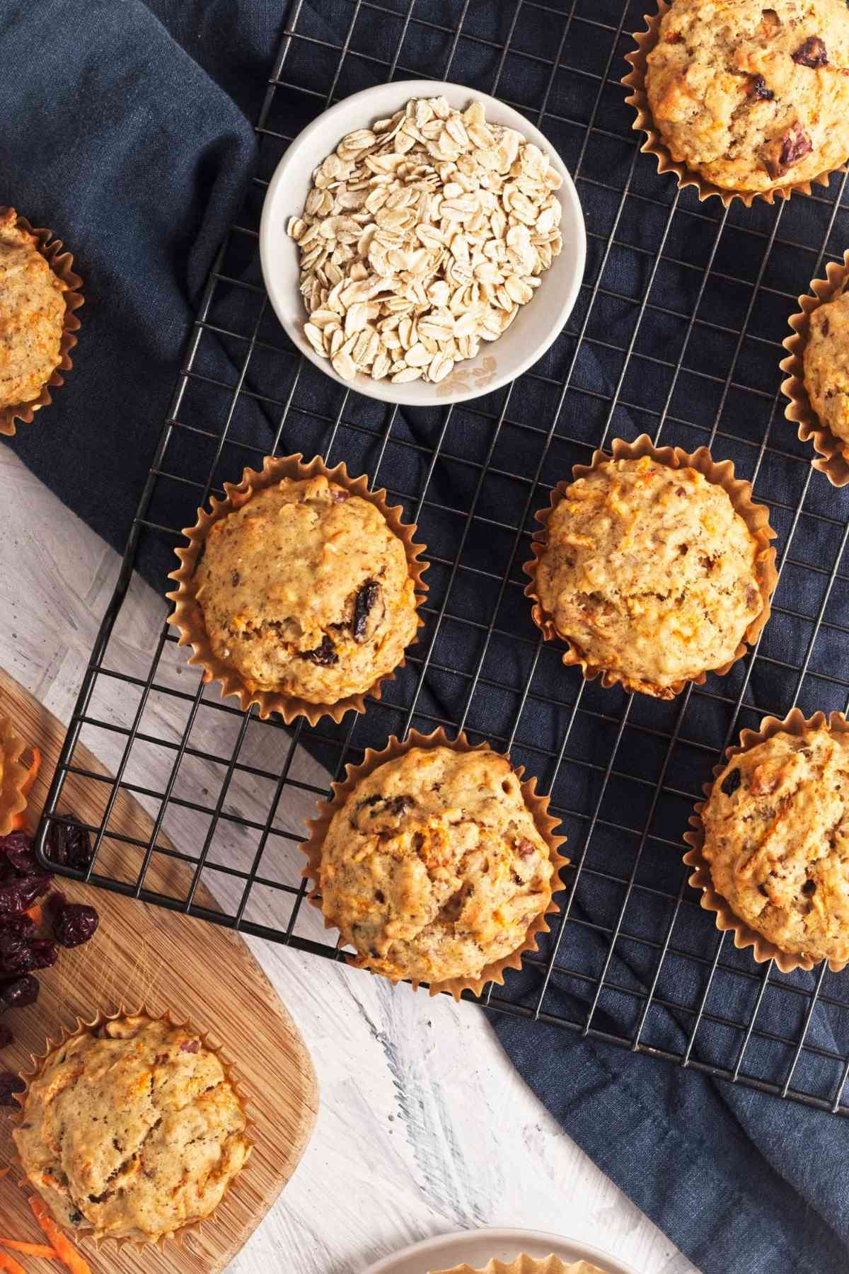 Overhead view of vegan carrot cake muffins on a cooling rack with rolled oats nearby