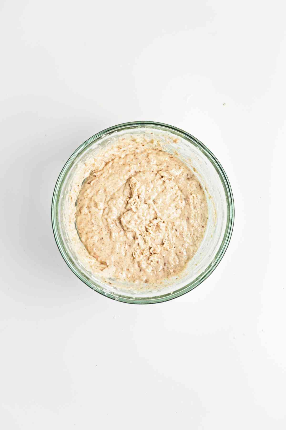 Wet and dry ingredients mixed in a glass bowl.