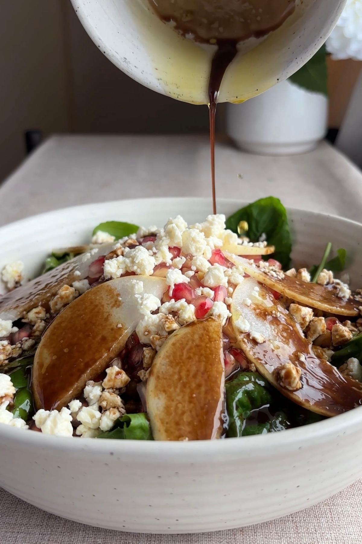 Balsamic dressing being poured over the assembled pear salad just before serving.