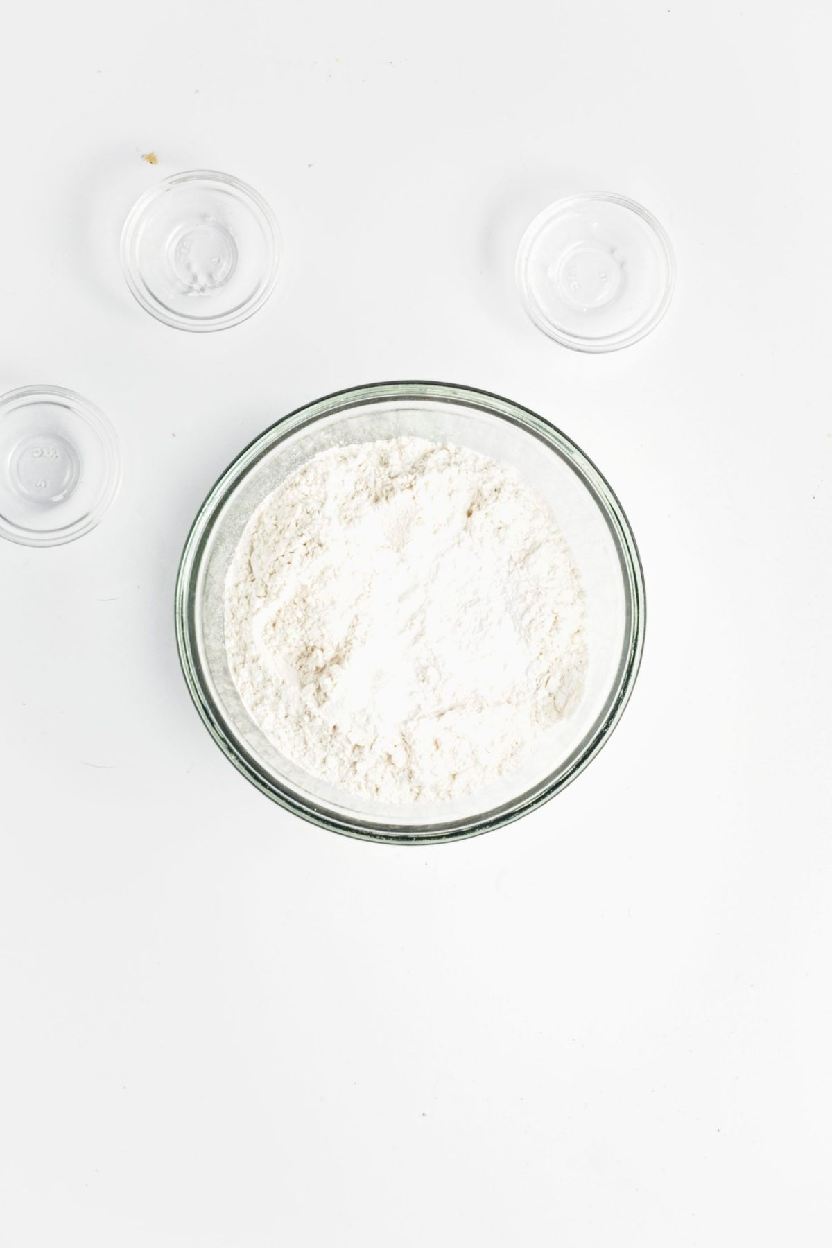 Dry muffin ingredients combined in a glass bowl, including flour, sugar, baking powder, baking soda, and salt.