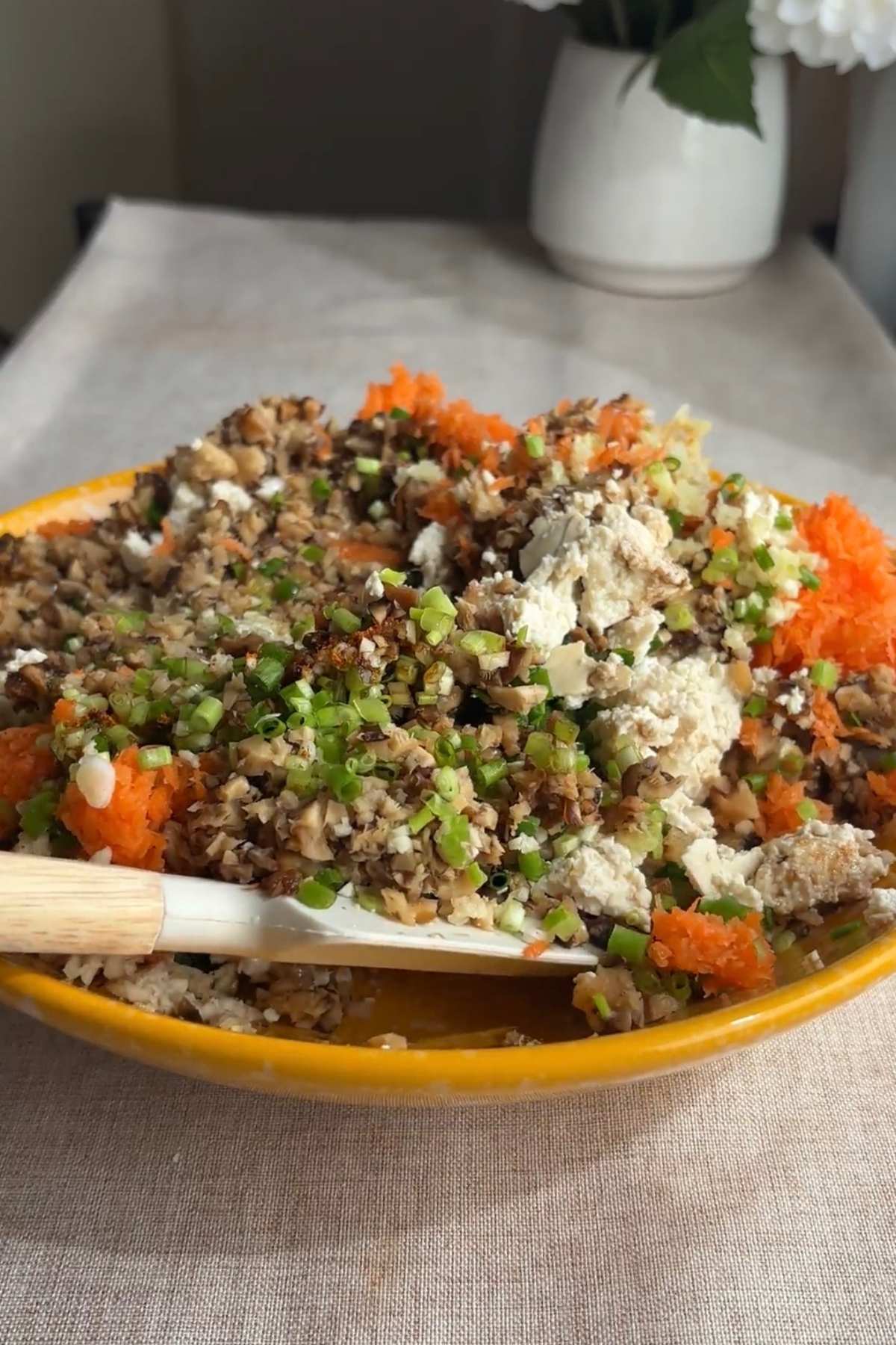 Bowl of dumpling filling with crumbled tofu, finely chopped mushrooms, carrot, and scallions.