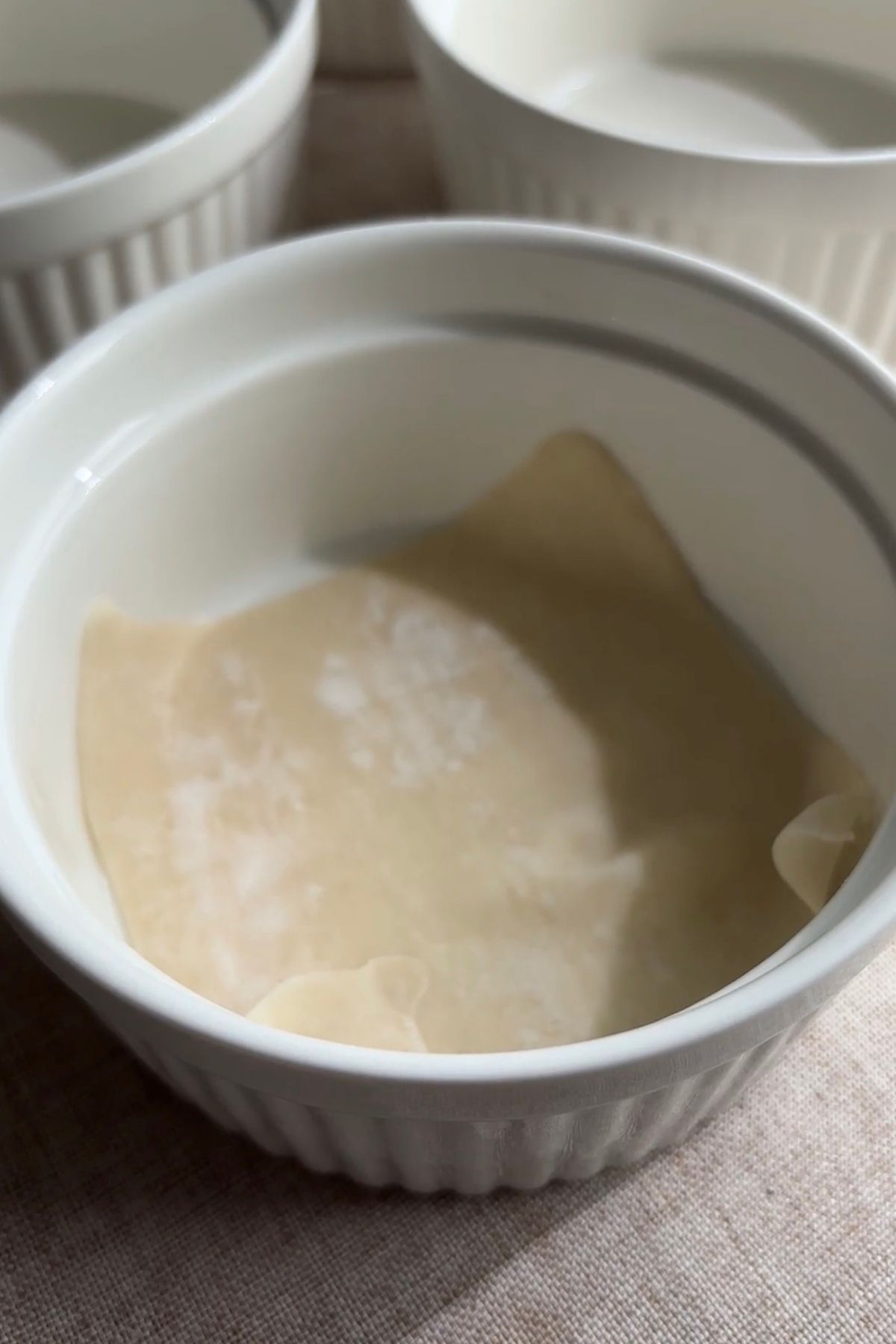 Empty white ramekin lined with a single wonton wrapper pressed into the base and sides.