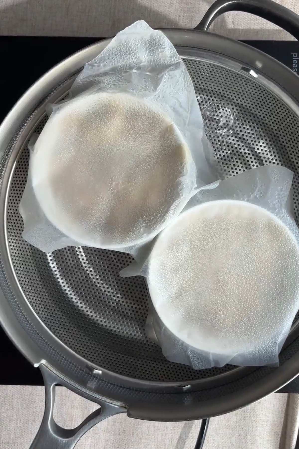 Covered ramekins placed in a steamer basket, wrapped with parchment paper.