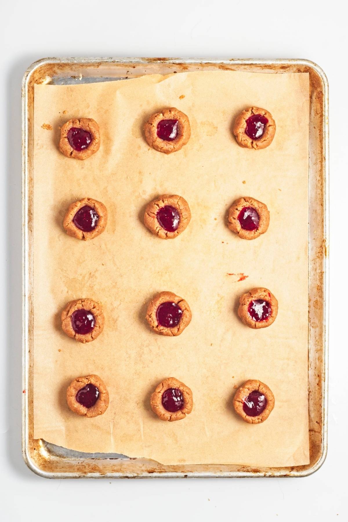 Strawberry jam spooned into cookie thumbprints before baking