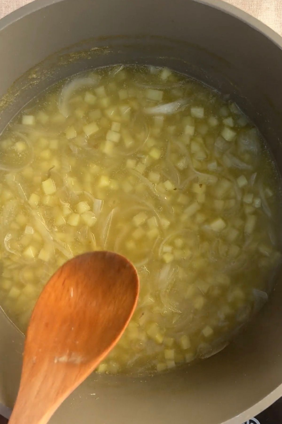 Potatoes simmering in broth until tender and fully cooked.