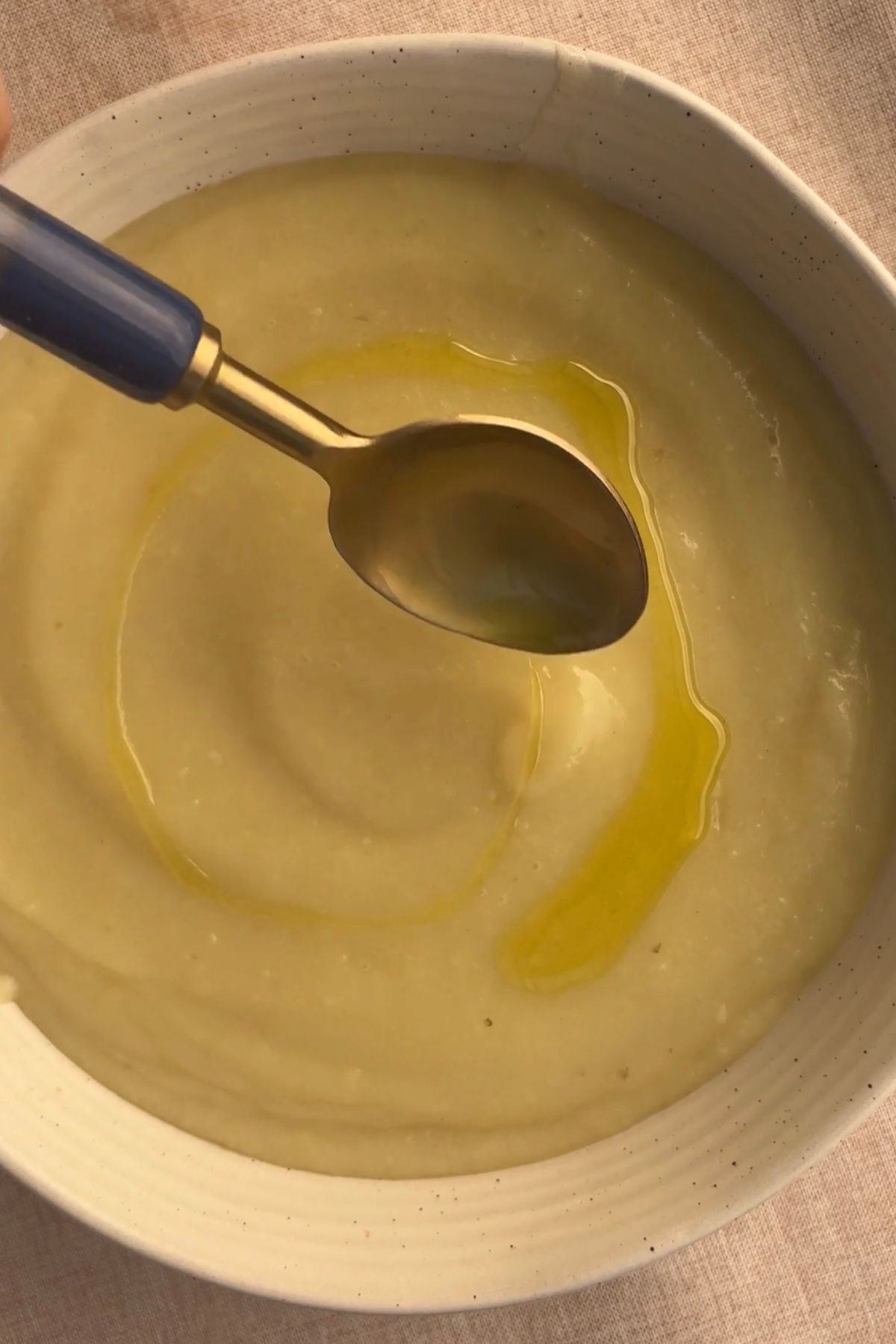 Finished potato soup topped with olive oil and black pepper, ready to serve.
