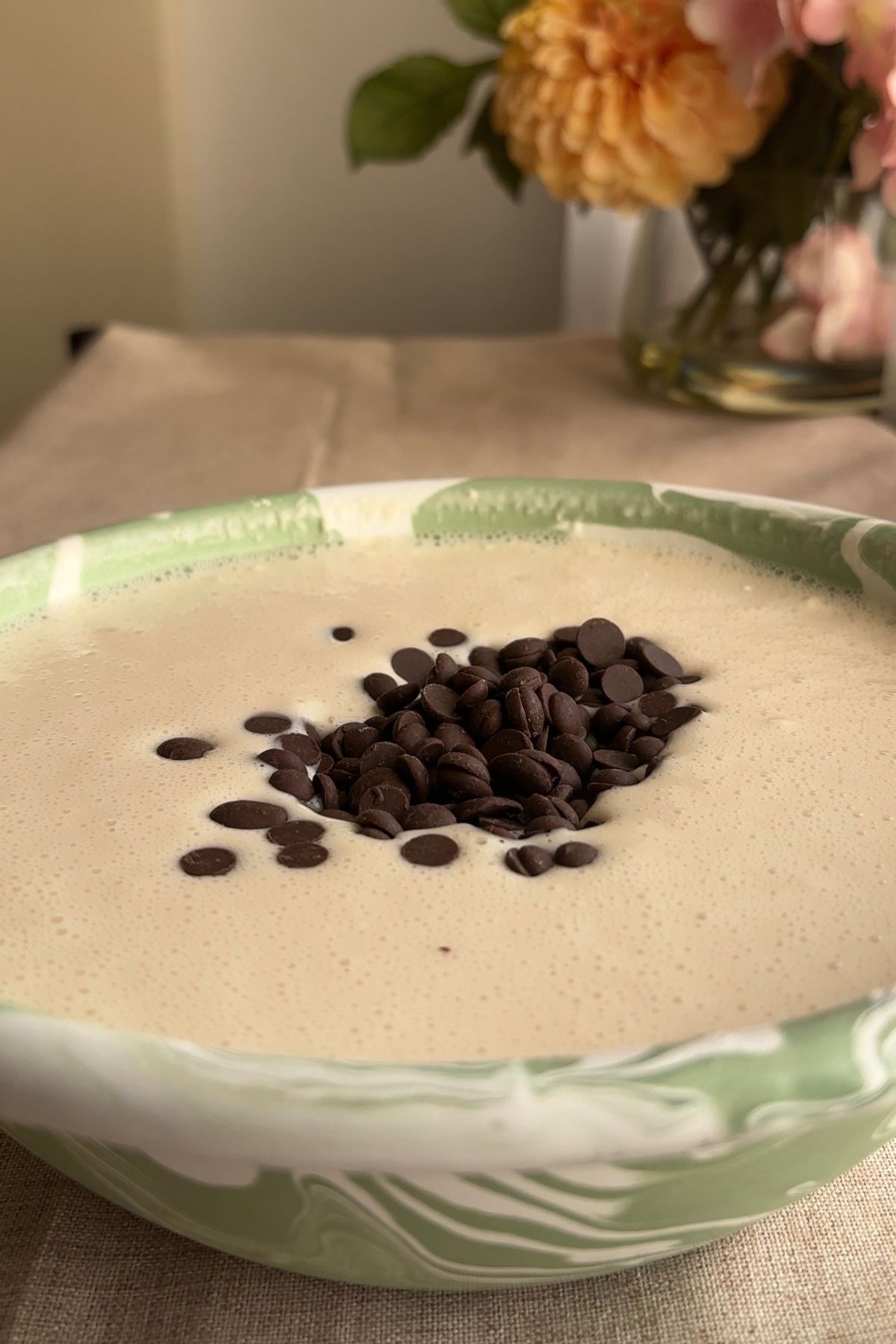 Chocolate chips scattered over pancake batter in a mixing bowl.