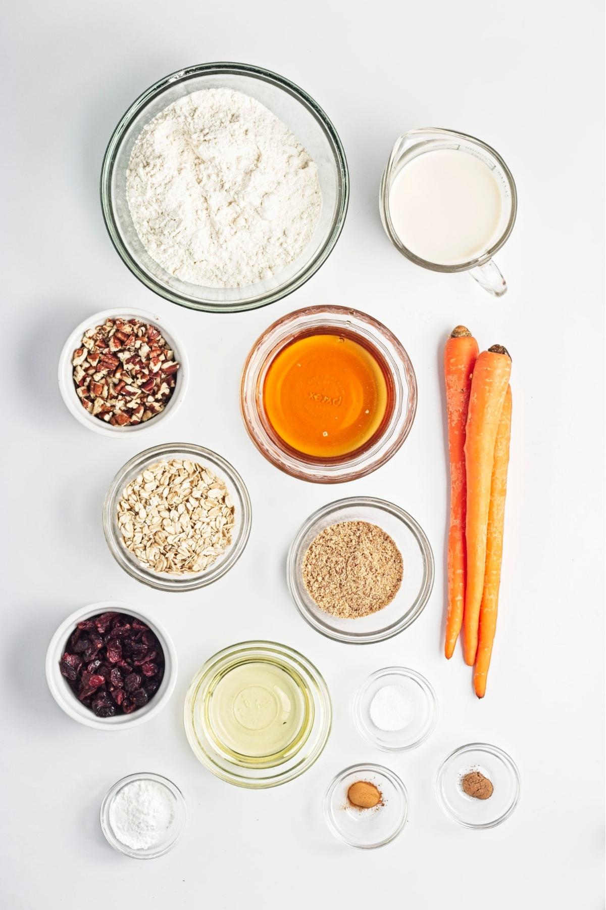Flat lay of vegan carrot cake muffin ingredients including carrots oats flour oil and maple syrup