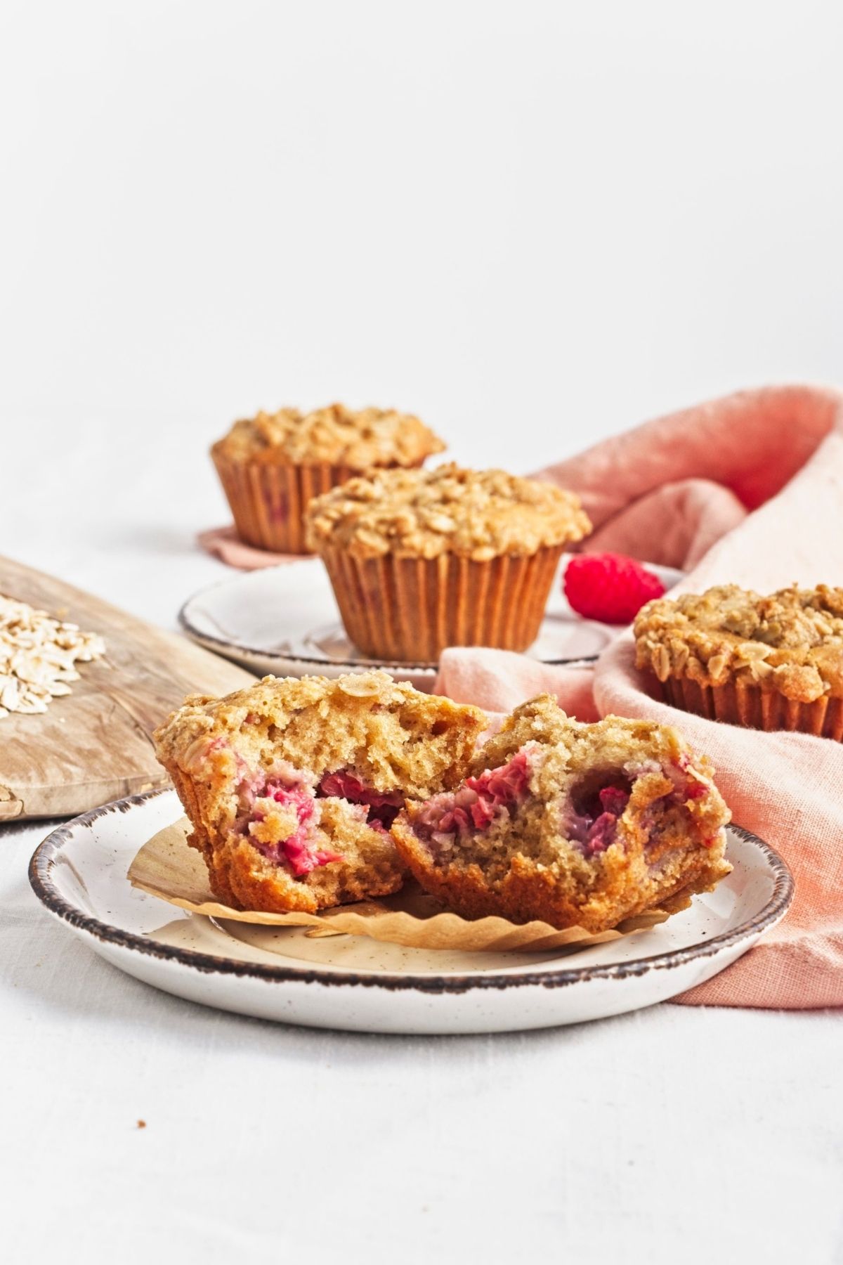 Sliced vegan raspberry oat muffins with a golden oat streusel topping on a white plate