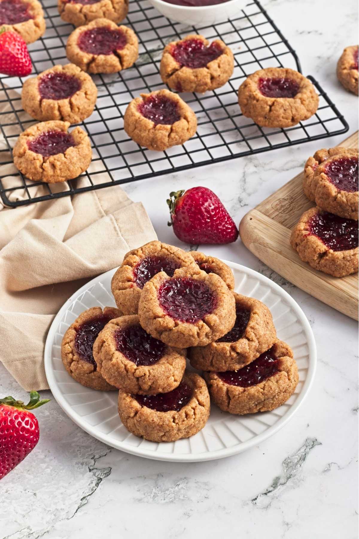 Strawberry almond thumbprint cookies with jam centers arranged on a plate