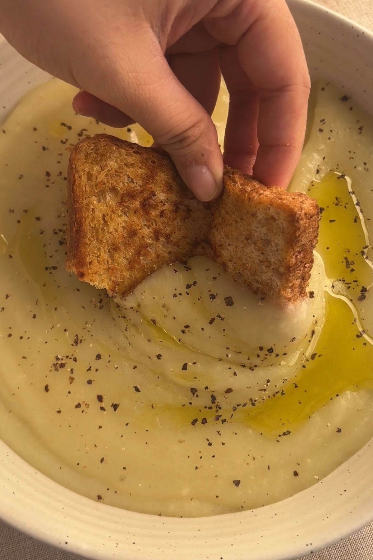 Rustic bowl of smooth potato soup served warm with olive oil and black pepper.