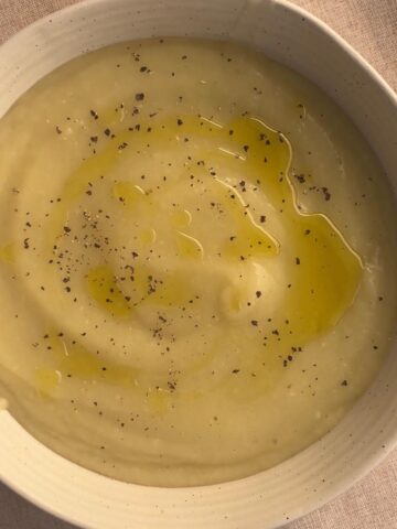 Creamy three-ingredient potato soup finished with a drizzle of olive oil and cracked black pepper in a ceramic bowl.