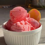 Three scoops of pink sorbet stacked in a white ramekin, with a smooth, slightly icy texture.