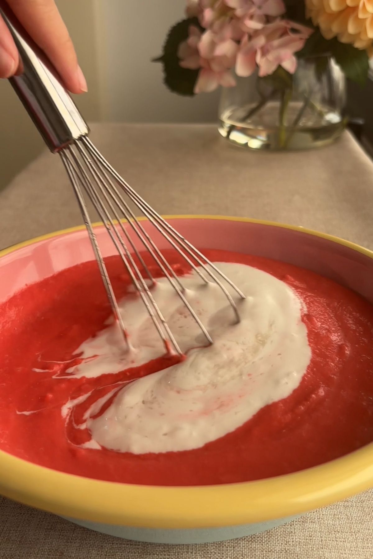 Whisk stirring coconut cream into bright pink guava purรฉe.