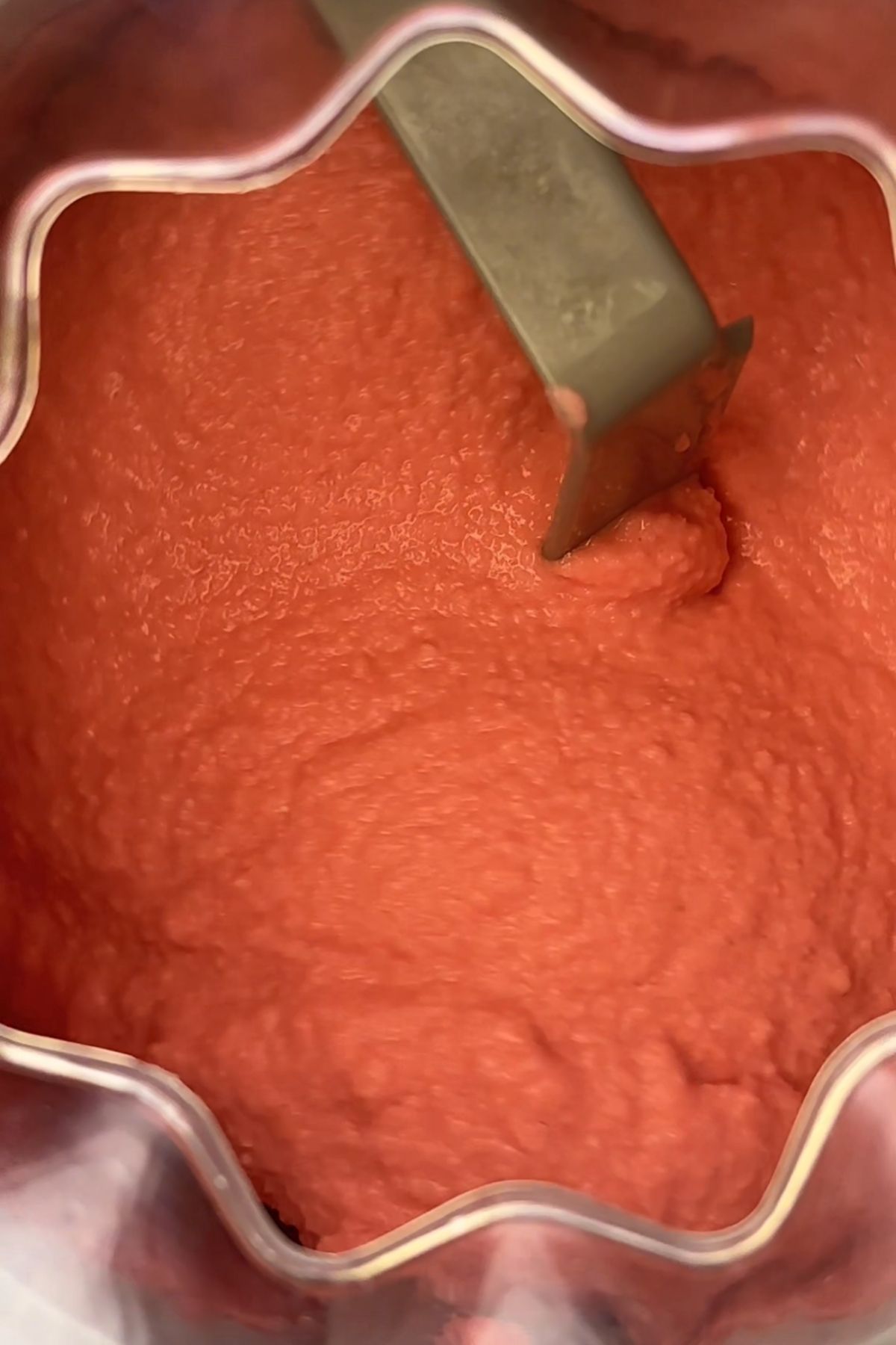 Thick pink sorbet mixture in an ice cream maker bowl.