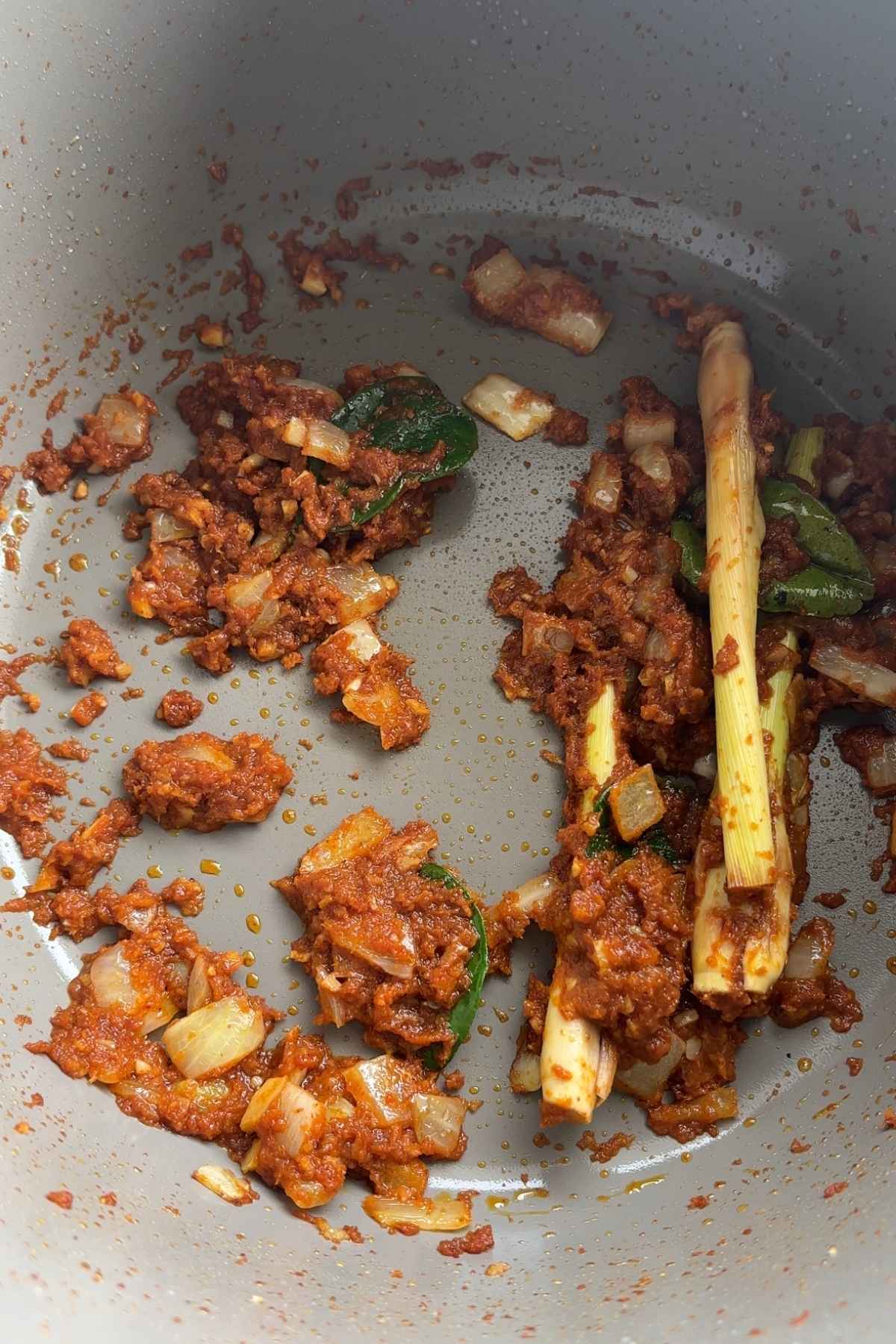 Cooked curry paste with onion and aromatics sautรฉing in a pot.