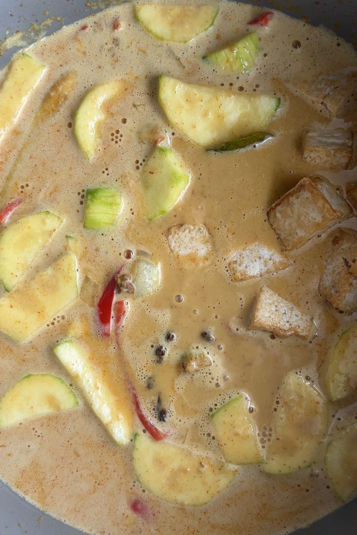 Finished yellow curry with vegetables and tofu simmering in a creamy sauce.