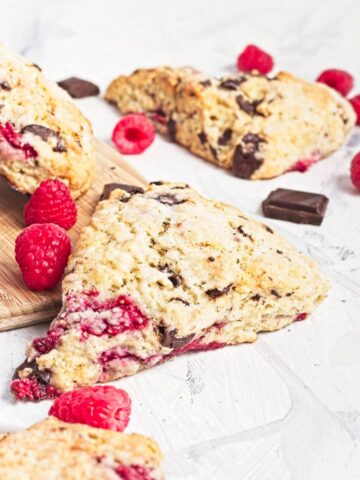 Close-up of a scone showing jammy raspberries and melted dark chocolate inside.