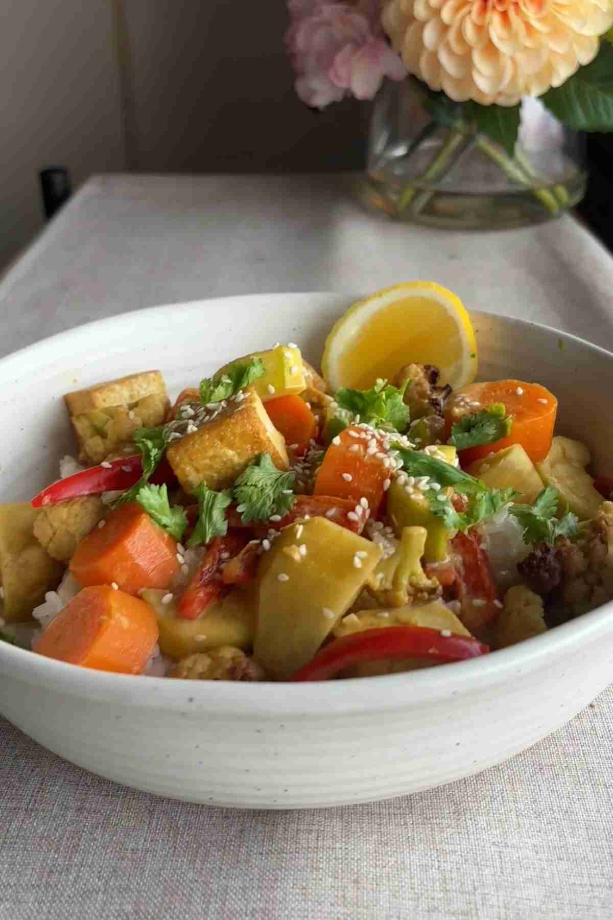 Creamy yellow curry with tofu, sweet potato, cauliflower, carrots, and rice, finished with herbs and sesame seeds.