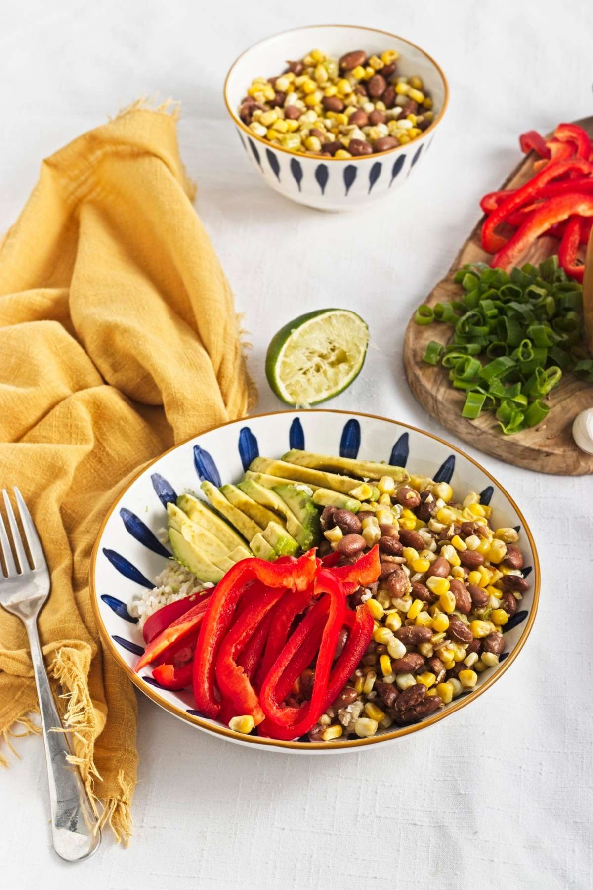 Vegan brown rice bowl with corn, pinto beans, avocado slices, and red bell pepper