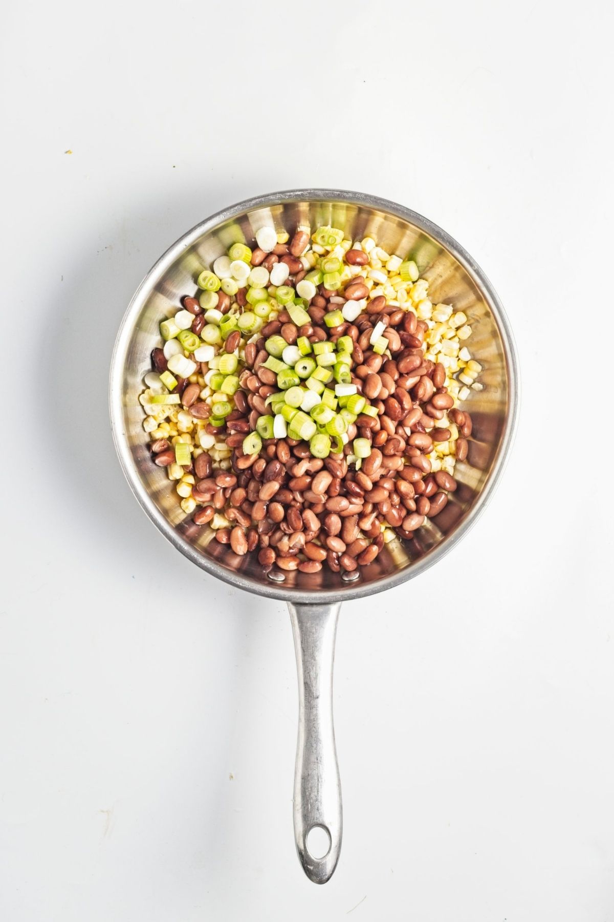 Pinto beans, corn, and green onions in a skillet