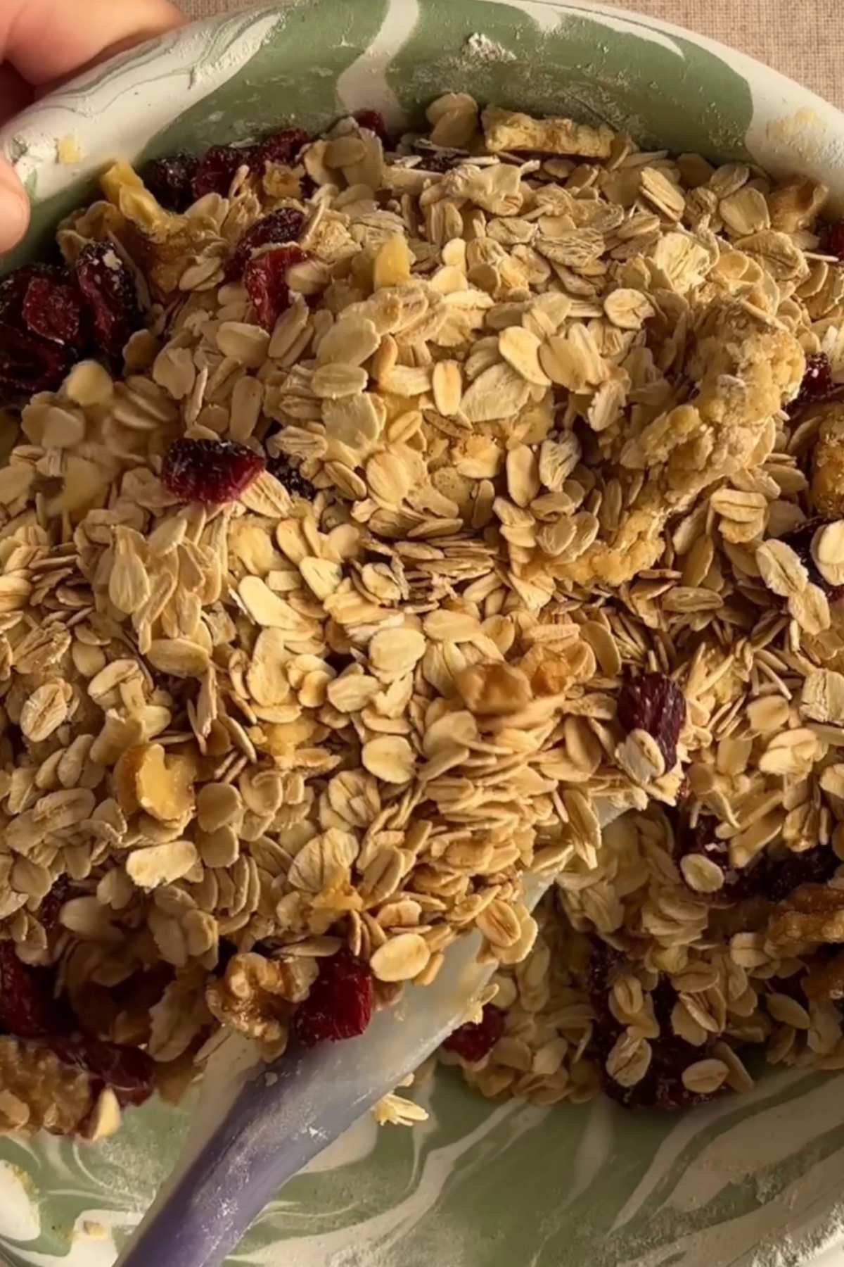 Rolled oats, dried cranberries, and chopped walnuts in a mixing bowl.