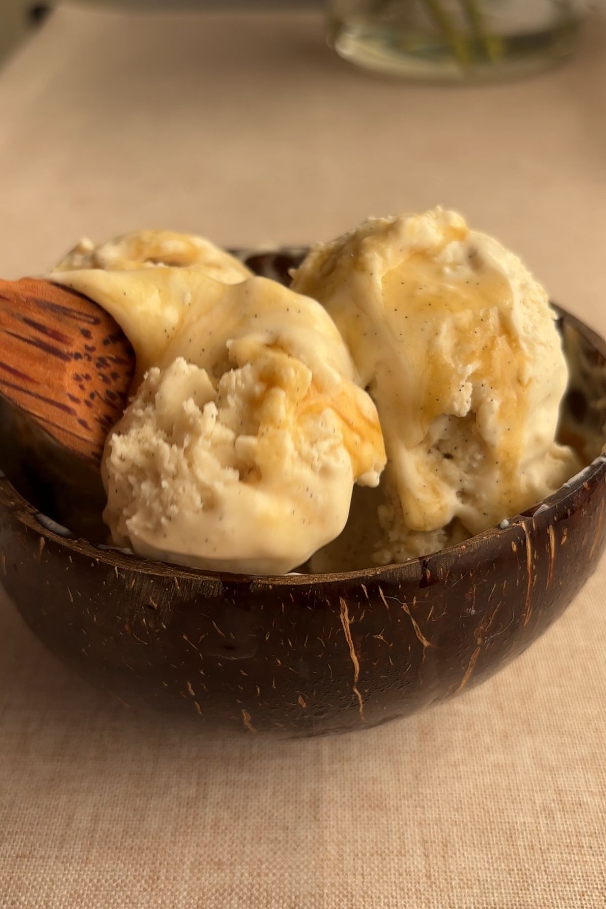 Scoops of coconut vanilla bean ice cream in loaf pan with ice cream scoop