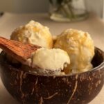 Vegan coconut vanilla bean ice cream with visible vanilla specks in coconut bowl