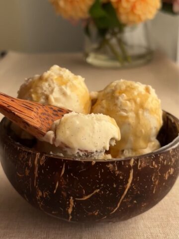 Vegan coconut vanilla bean ice cream with visible vanilla specks in coconut bowl