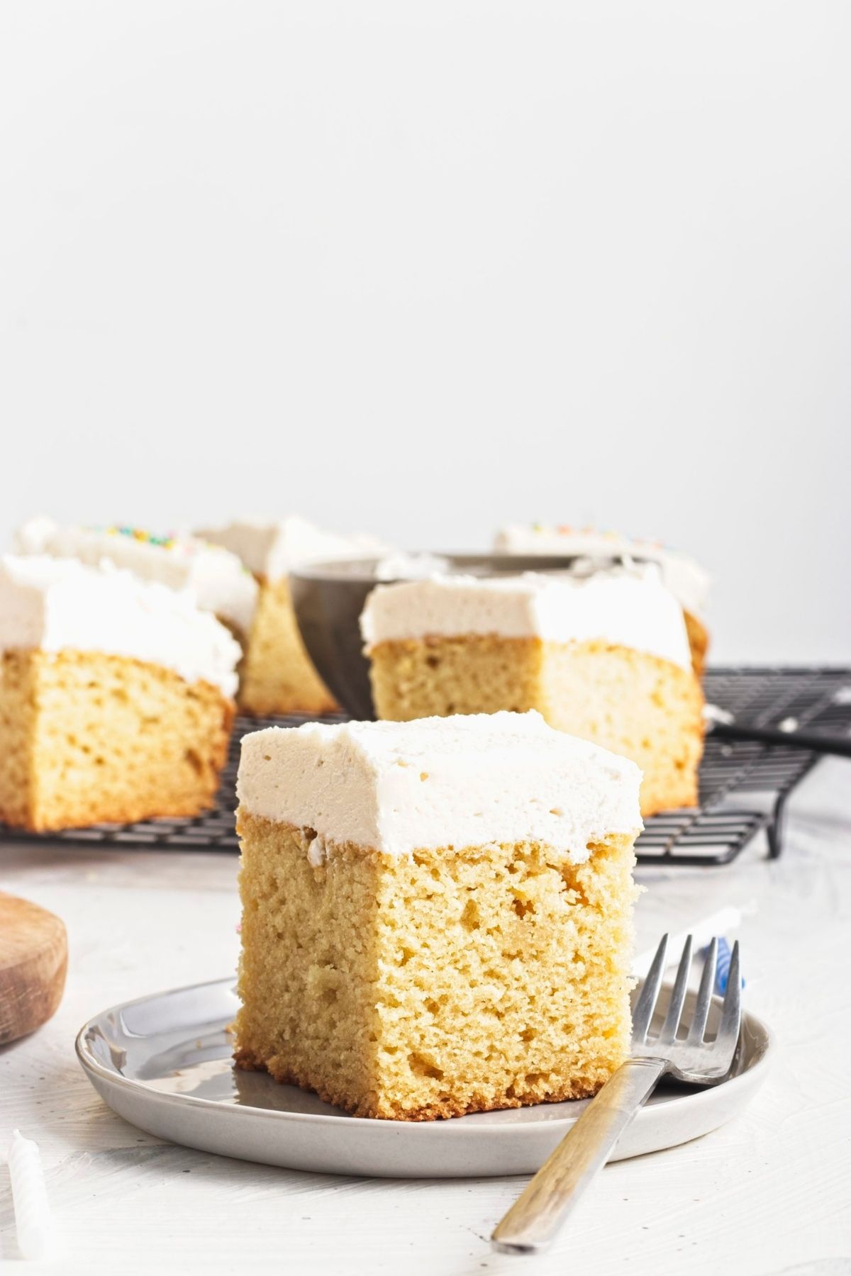 A frosted cake square on a plate with a fork.