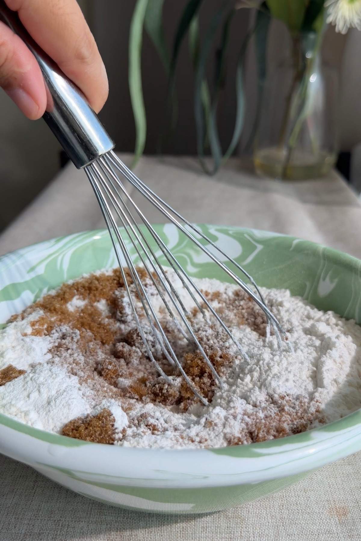 Whisk resting in a bowl of flour and brown sugar.