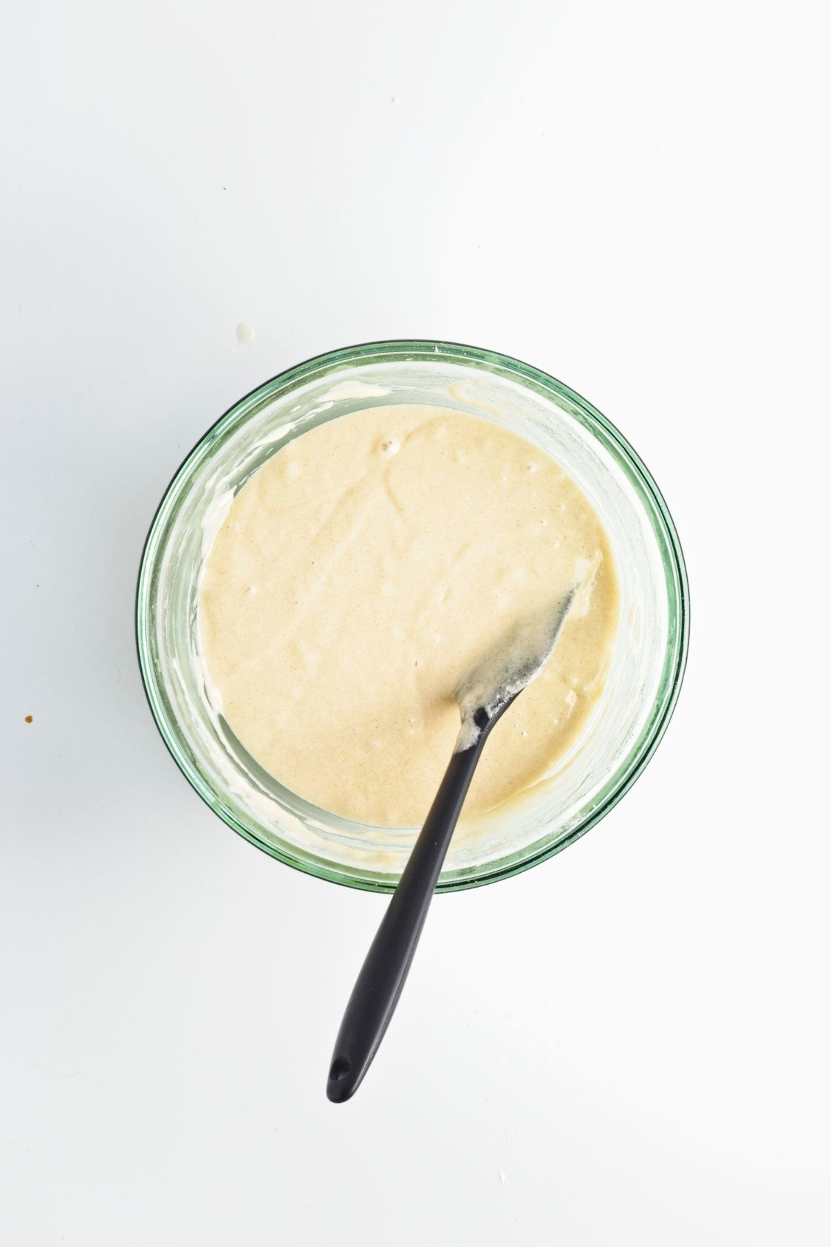 Cake batter mixed in a glass bowl with a spatula.