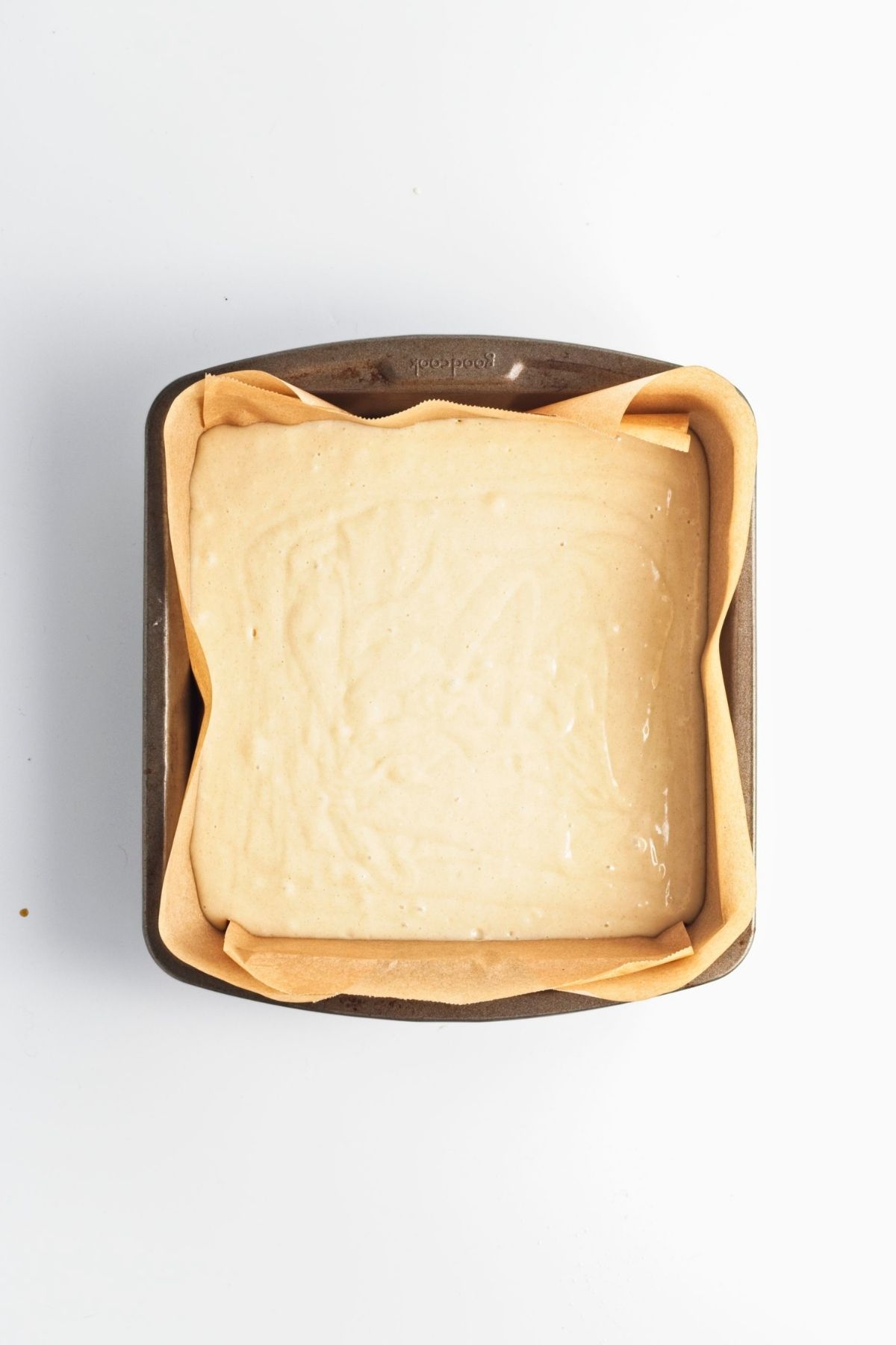 Cake batter smoothed into a parchment-lined pan.
