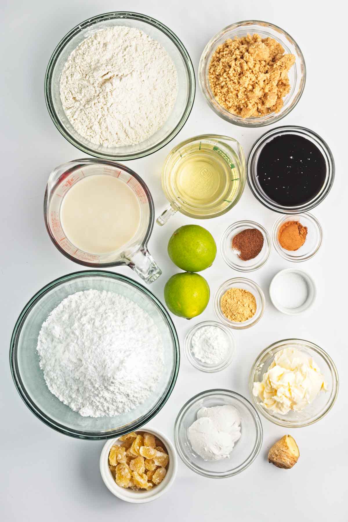 Baking ingredients arranged in bowls with limes and fresh ginger.