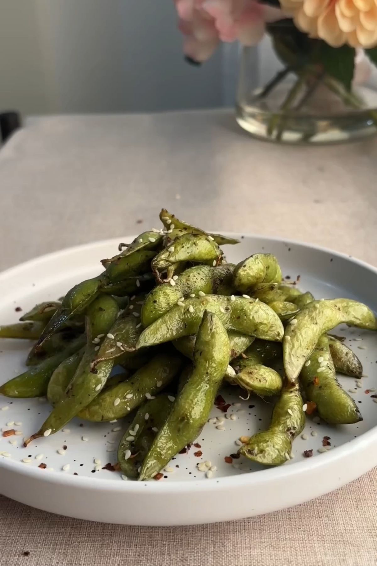 Air fried edamame pods topped with sesame seeds and chili flakes.