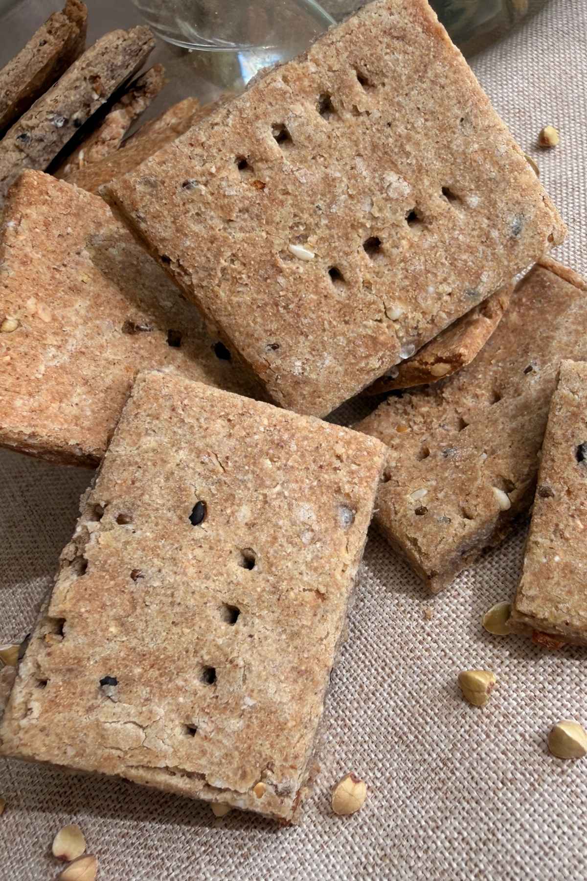 Close-up of crisp homemade crackers stacked on a cloth surface.