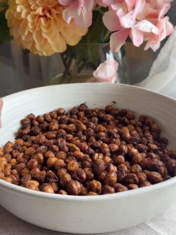 Crispy roasted chickpeas scattered across a shallow white bowl.