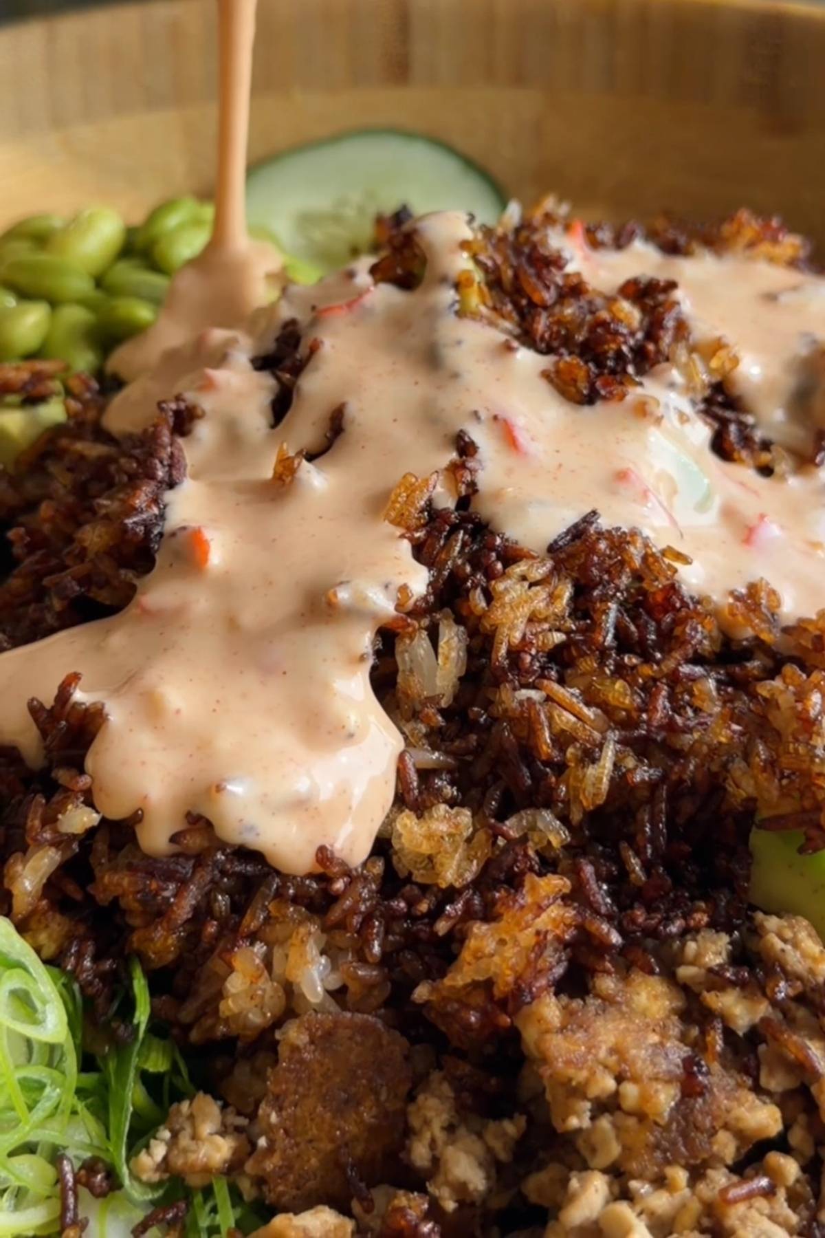 Spoonful of crispy rice salad with cucumber, avocado, creamy dressing, and chopped peanuts.