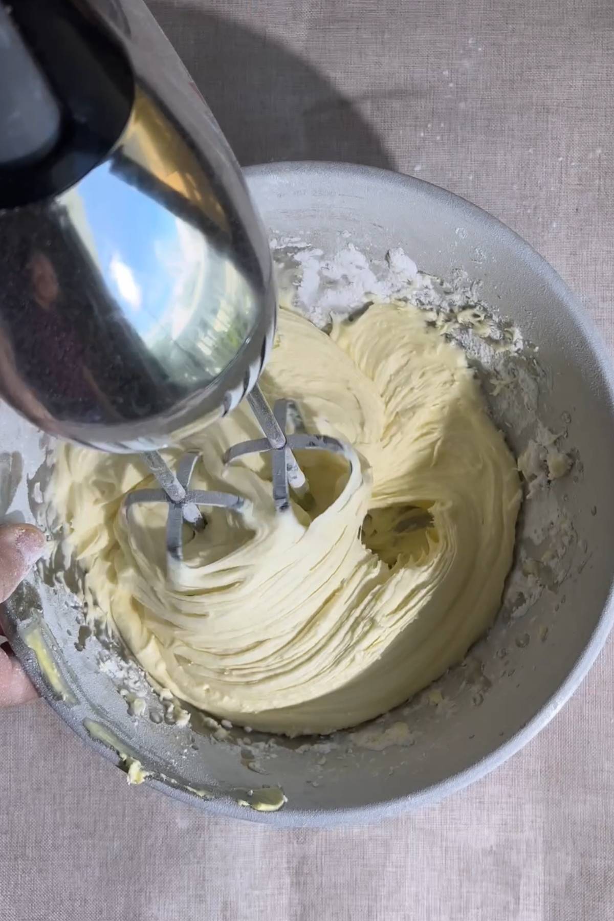 Buttercream being beaten with an electric hand mixer.