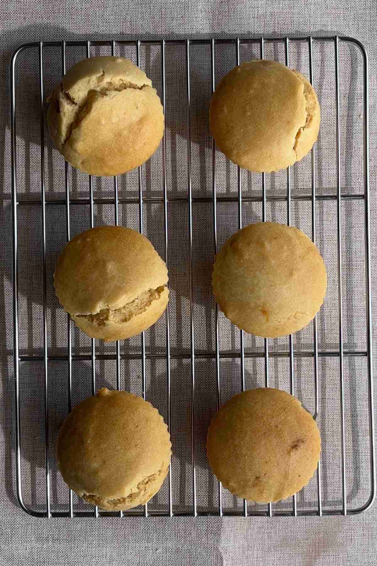 Six baked cupcakes cooling on a wire rack.