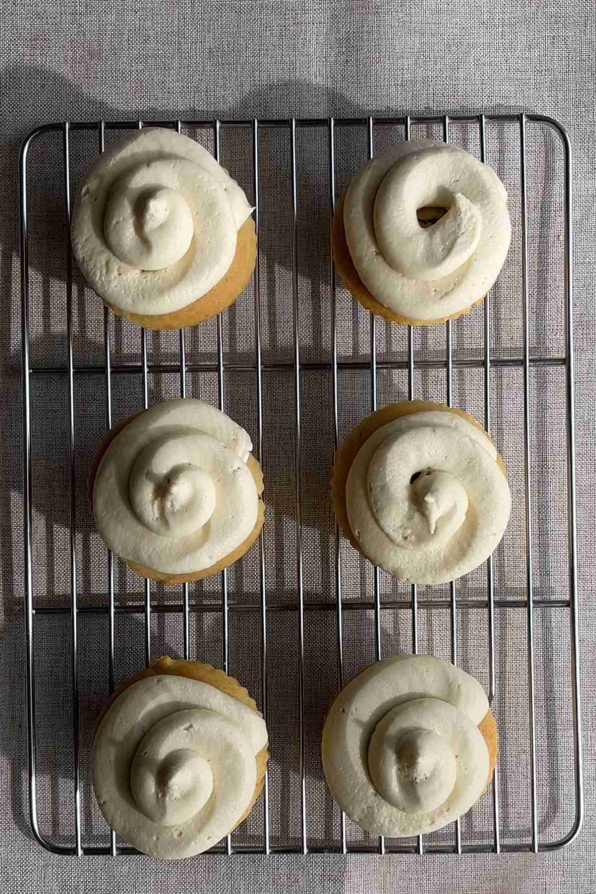 Six frosted cupcakes on a cooling rack.