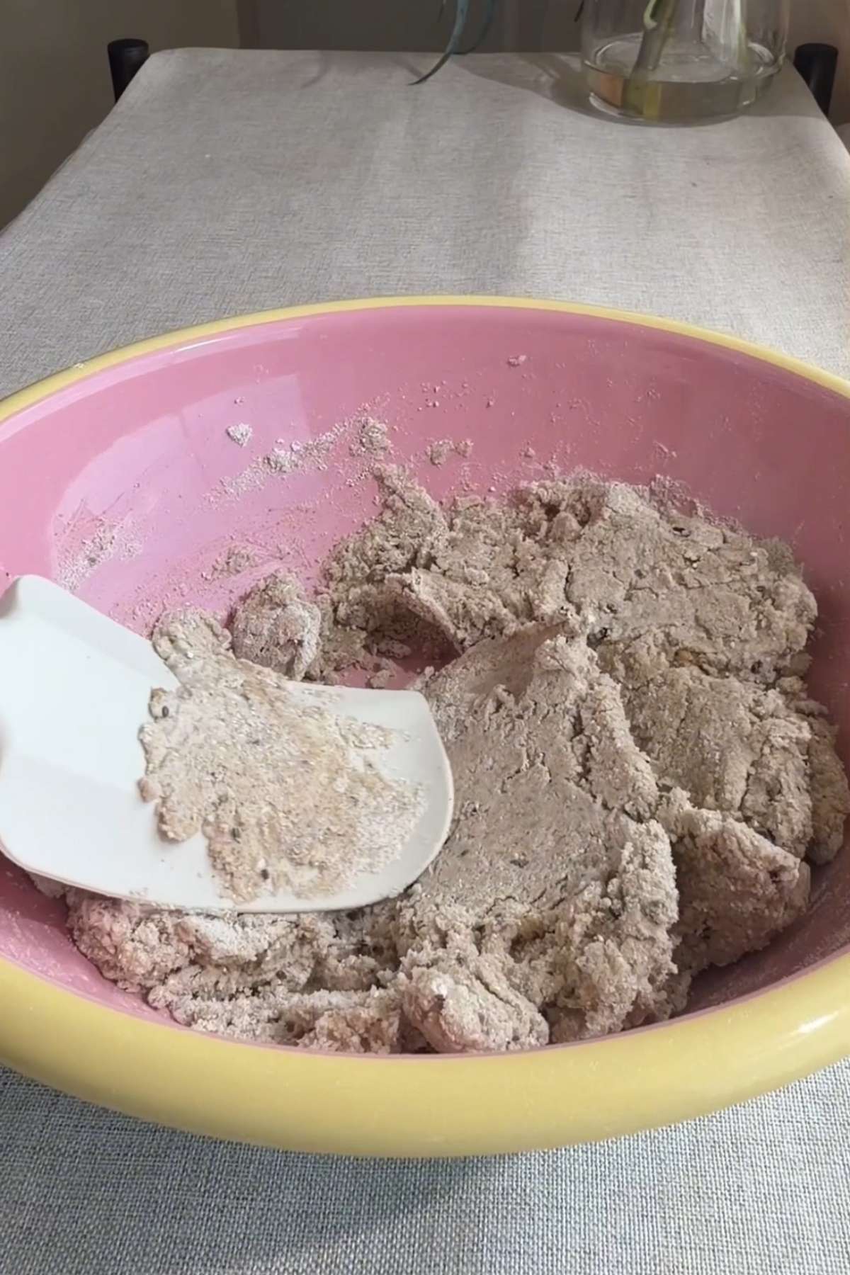 Buckwheat cracker dough mixed in a pink bowl with a white spatula.