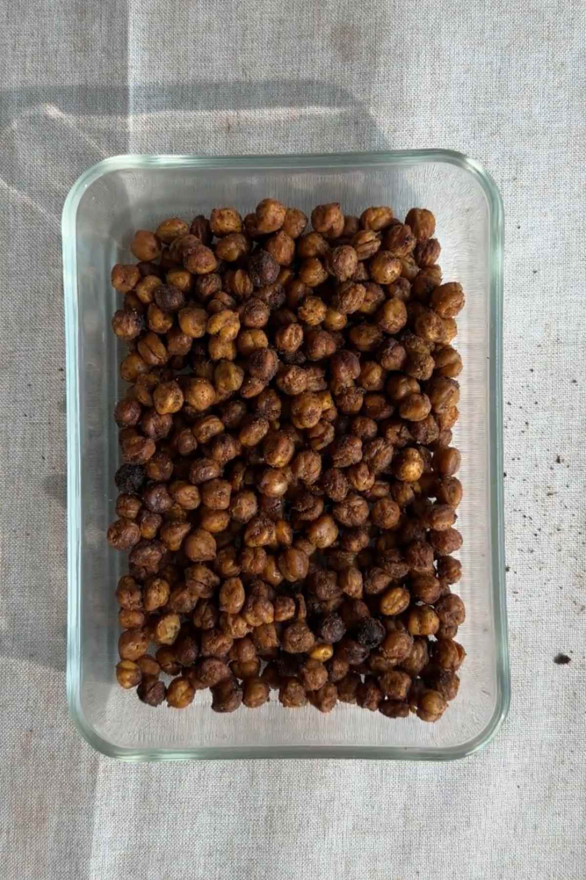 Crispy roasted chickpeas in a glass container viewed from above.