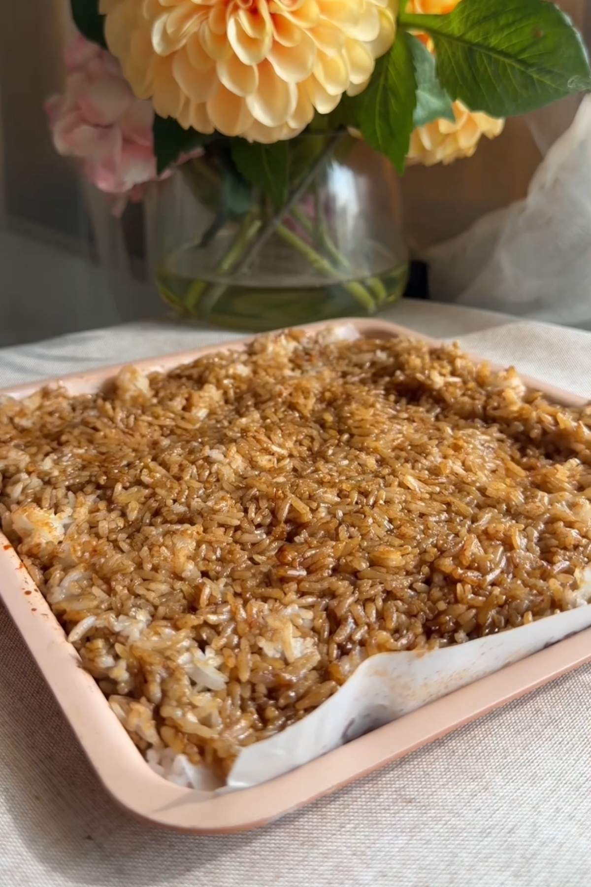 Seasoned rice spread in a parchment-lined baking dish before baking.