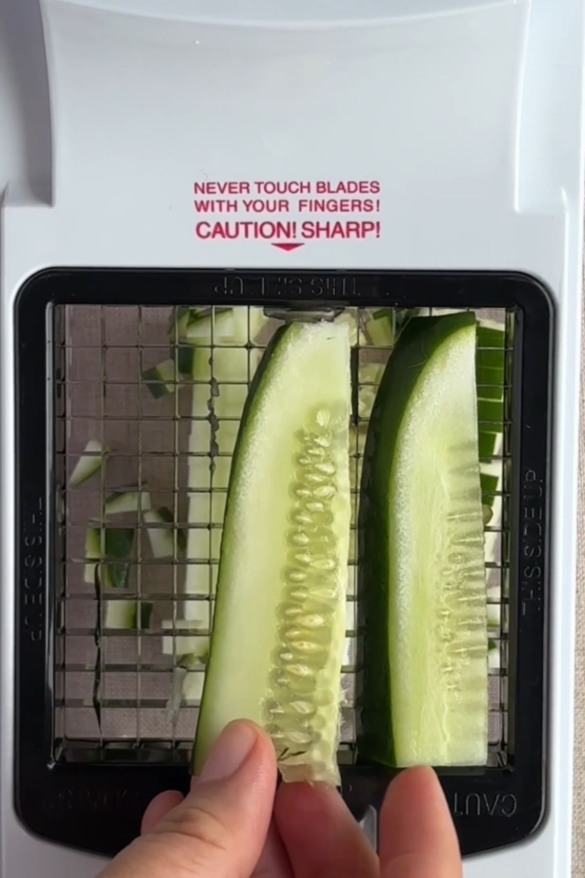 Cucumber being diced with a vegetable chopper.