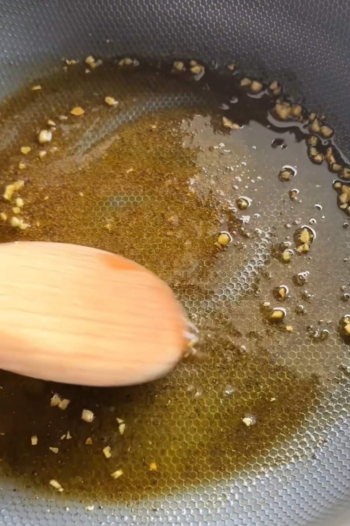 Garlic and seasonings warming in olive oil in a frying pan.